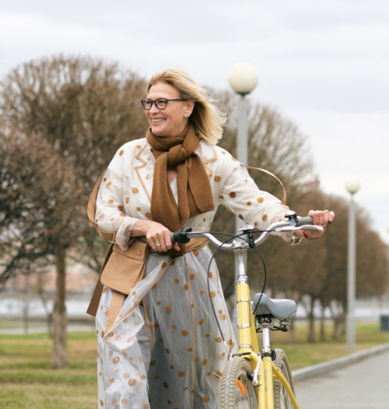 woman walking with bike in raincoat